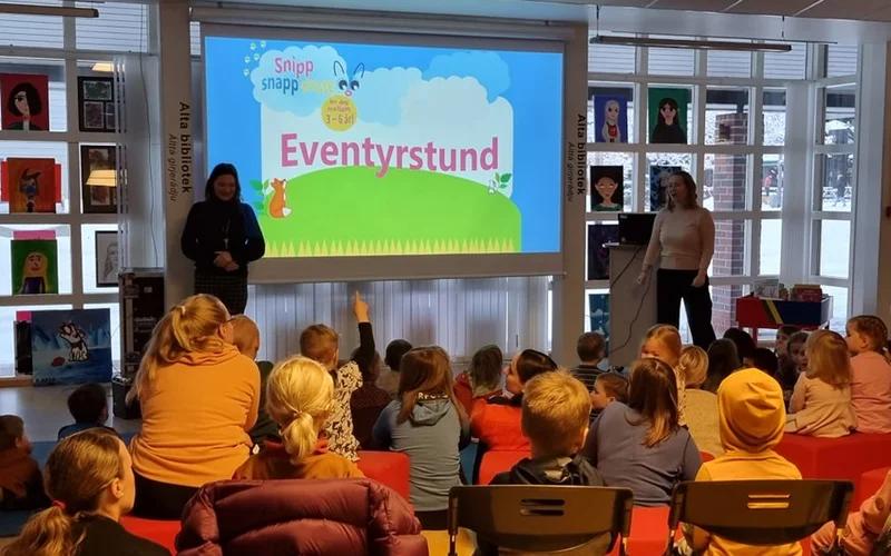 Bilde av barne- og ungdomsbibliotekarene Annelene og Monica foran mange barn.